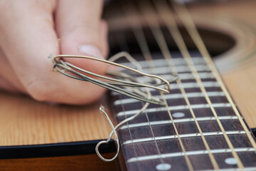Old used guitar strings near new changed ones on the guitar. Concept of changing bad old strings on...