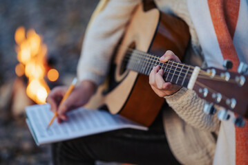 Close up on acoustic guitar of a girl guitarist composing new song. Young musician playing the...