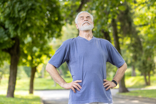 Senior man taking a deep breath during outdoor exercise in a sunny park