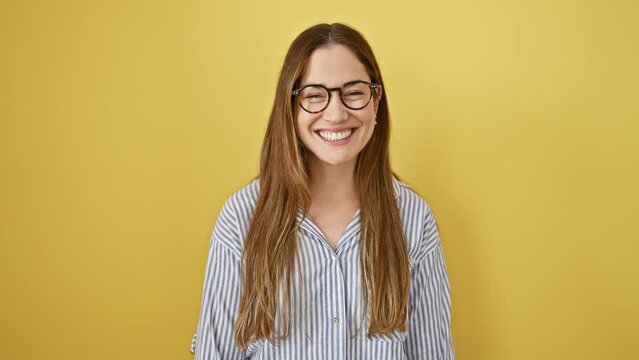 Hilarious portrait of a young brunette woman blown up with a puff of air, wearing glasses, making funny faces, cheeks inflated. isolated on a yellow background.