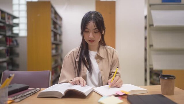 young asian student woman doing lesson exam at college library
