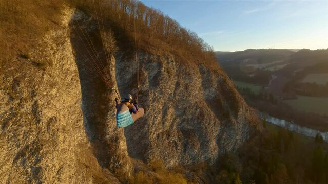 Adventure Flying proximity by rocky cliff in spring nature at golden sunset, paragliding beauty