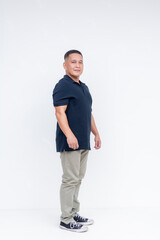 Fototapeta premium Full body portrait of a self-assured middle-aged Asian man in casual attire standing against a white background.