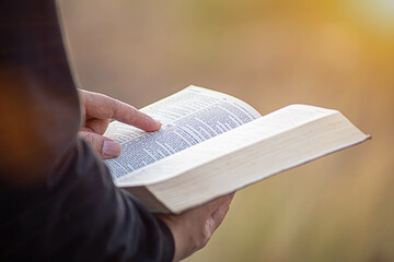 young man pointing to a bible topic and read the Bible on Sundays to receive the blessings of God. - obrazy, fototapety, plakaty
