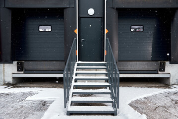 Entrance to the warehouse. Metal stairs and roller doors for cars