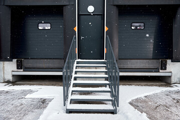 Entrance to the warehouse. Metal stairs and roller doors for cars