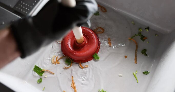 plumber cleans clogged kitchen sink with plunger