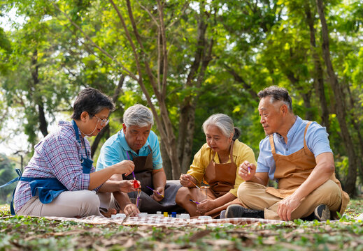 A group of Asian senior people enjoy painting cactus pots and recreational activity or therapy outdoors together  at an elderly healthcare center, Lifestyle concepts about seniority - Powered by Adobe