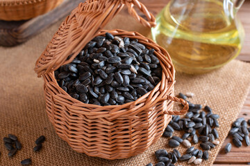 Pile of black roasted salty sunflower seeds with oil on wooden table, nut concept.