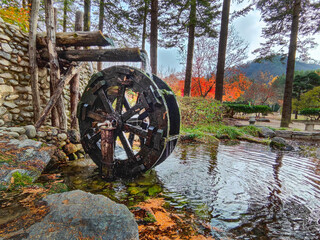 A water wheel and an artificial pond in a park on Nami Island, Naminara Republic. A warm cloudy autumn day