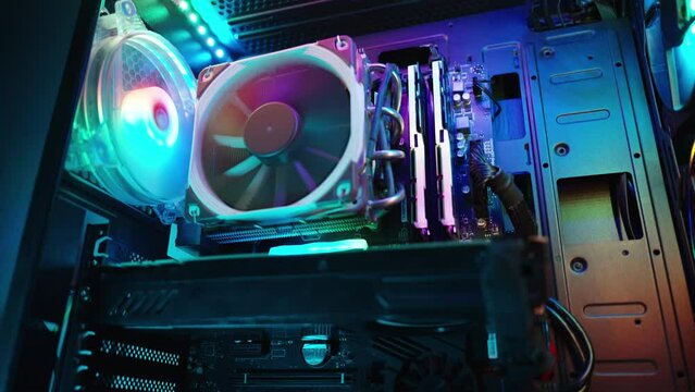 In the darkness, a gaming desktop PC shimmers with rainbow light, close-up of the internal components.
