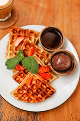 Waffles with strawberries and chocolate topping, top view. The concept of delicious breakfast. Stylish food design for advertising baked goods and appetizing food
