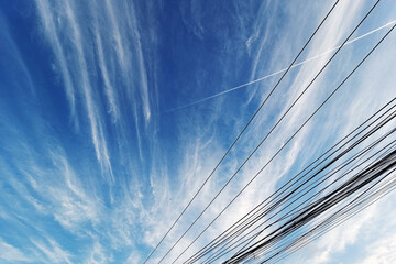 Blue sky with white clouds on wire background. Beautiful sky view from below