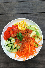 Salad with tempeh and vegetables on wooden background top view