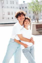 Young smiling beautiful woman and her handsome boyfriend in casual summer white t-shirt and jeans clothes. Happy cheerful family. Female having fun. Couple posing in street at sunny day
