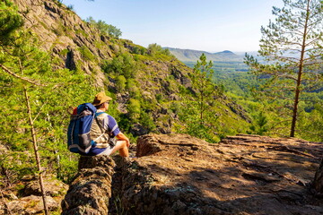 Fototapeta na wymiar a young man rests on the rocks in the mountains of the Southern Urals on a summer sunny day