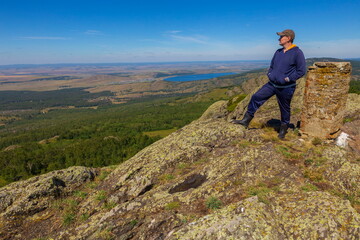 Naklejka premium a young man rests on the rocks in the mountains of the Southern Urals on a summer sunny day