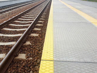 Empty railway station with rail tracks. Train platform