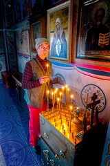 Russia Saraktash August 20, 2022: beautiful mature woman lights a candle in an Orthodox church