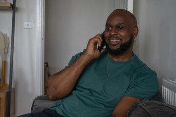 Smiling man talking on smart phone at home