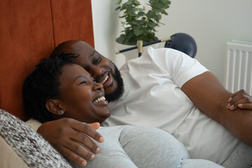 Smiling man embracing pregnant woman on bed - obrazy, fototapety, plakaty