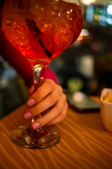 glass of sprits held up by a hand with enamel