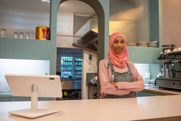 Fototapeta na wymiar Portrait of young woman in hijab working in cafe
