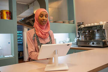 Young woman in hijab working in cafe