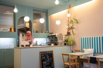 Young woman in hijab working in cafe