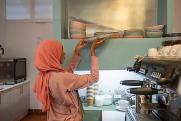 Fotobehang Young woman in hijab working in cafe © Cultura Creative