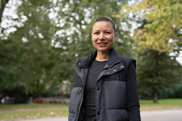 Fototapeta premium Portrait of smiling woman in sports clothing in park
