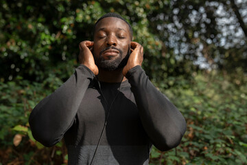 Portrait of athletic man with earbuds standing in park