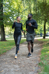 Smiling man and woman jogging in park