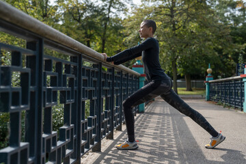 Athletic woman stretching legs on footbridge in park