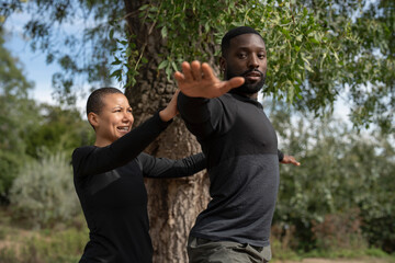 Yoga instructor assisting man practicing yoga in park