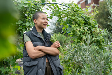 Portrait of woman with bunch of homegrown green bean in urban garden