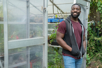 Portrait of smiling man standing in front of greenhouse