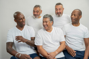 Group portrait of smiling senior men in white t-shirts against gray background