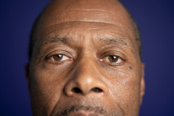 Close-up of man looking at camera against purple background