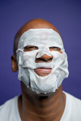 Portrait of man in facial mask against purple background