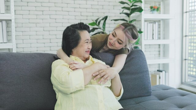 Surprised daughter hugs mother on sofa at home