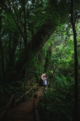 Young woman in white dress with umbrella decorated with wire lights in foggy forest