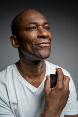 Portrait of man putting on perfume against gray background