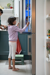 Little girl opening fridge