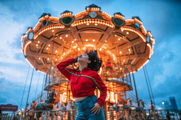 A woman in a red dress shakes her hair The background is an amusement park.