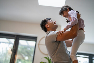 Father lifting daughter at home