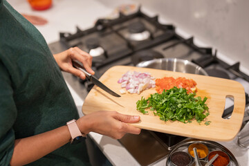 Woman holding cutting board with chopped vegetables