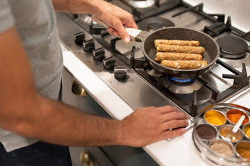 Man holding frying pan with sausages - obrazy, fototapety, plakaty