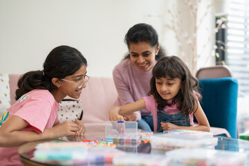 Mother with daughters playing with beads in living room