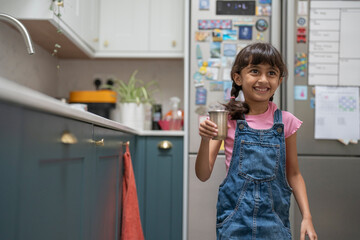 Little girl holding mug in kitchen